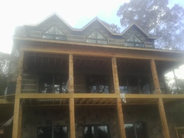 Dormers and porch framing on a large log home under construction — Roof Coating work by our crew in Krotz Springs