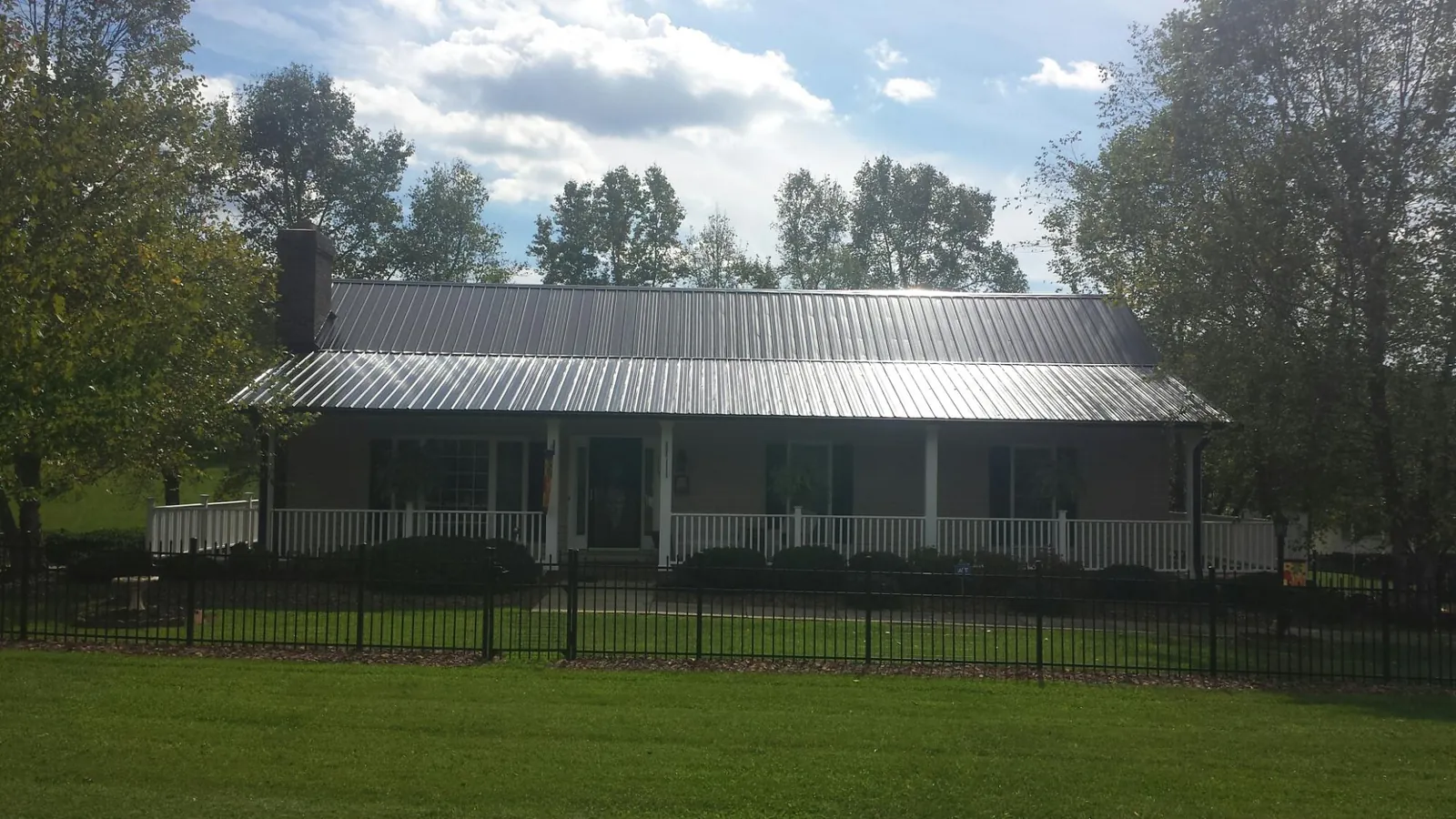 Gray metal roof on a brick ranch with a full width front porch — Gutter Guard Installation work by our crew in Krotz Springs