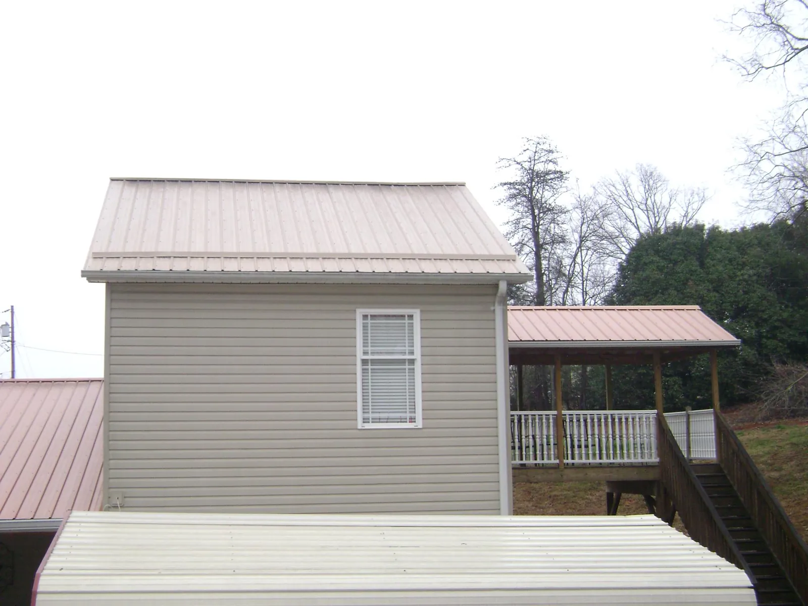 Tan metal roofs on a two story addition and attached porch, from a Roof Replacement job in Krotz Springs