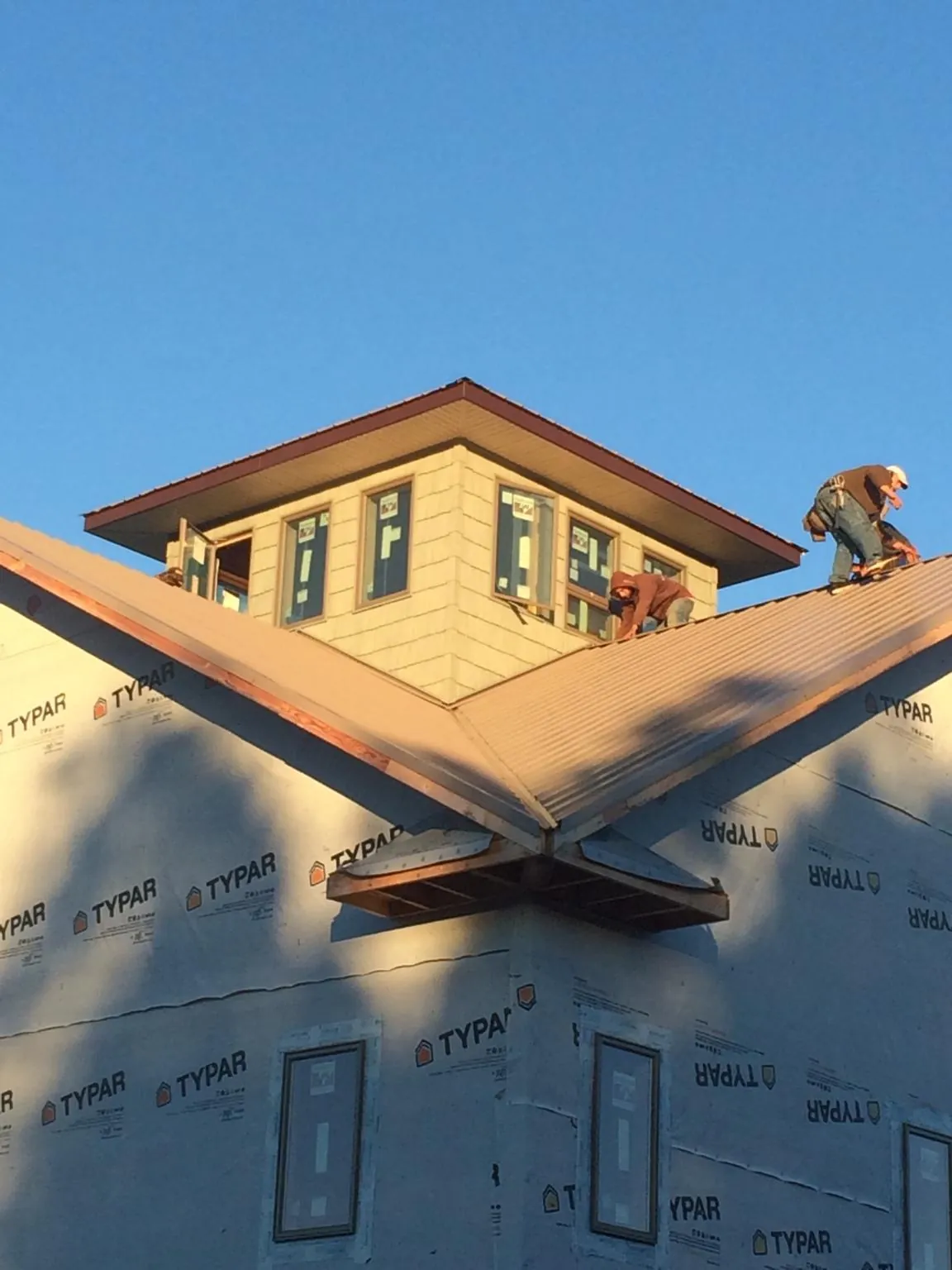 Roofers working around a rooftop cupola on a new metal roof at sunset — Roof Waterproofing in Krotz Springs by Roofing Brothers